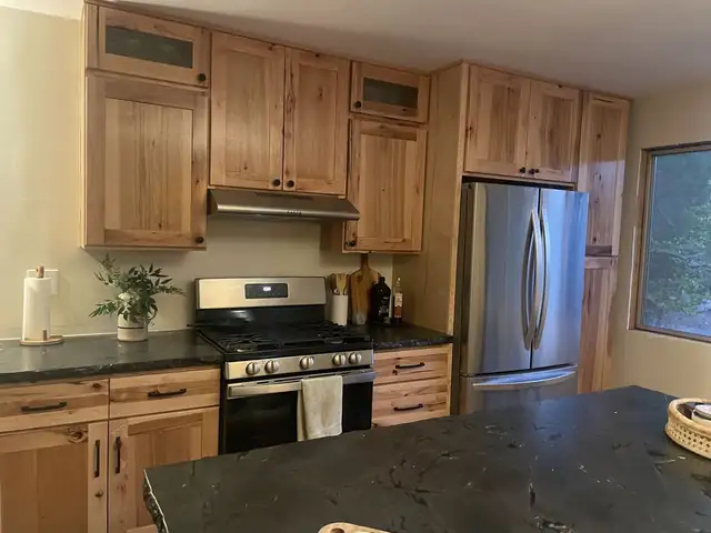 Natural wood shaker cabinets with glass-front uppers, dark granite countertops, stainless range and French-door refrigerator