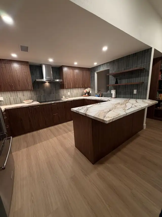 Dark walnut flat-panel kitchen with a marble-look island top and green vertical tile backsplash